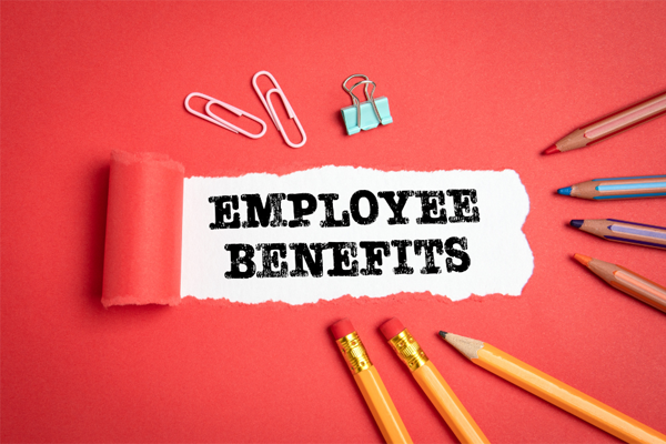 the words employee benefits on a red background with pencils and paper clips